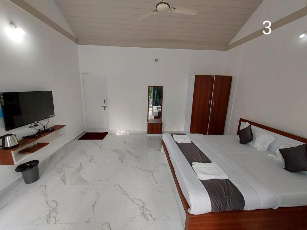 a bedroom with a large bed and a tv at Areca ranches home stay in Chikmagalūr