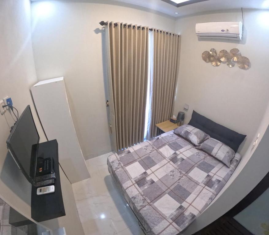 Dormitorio pequeño con cama y TV en Pelemsewu Living Homestay Jogja, en Jarakan