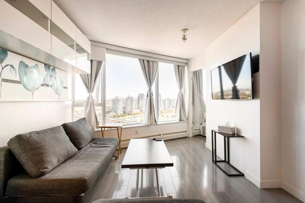 uma sala de estar com um sofá e uma grande janela em Downtown Living with Location Views Pool Workspace em Vancouver