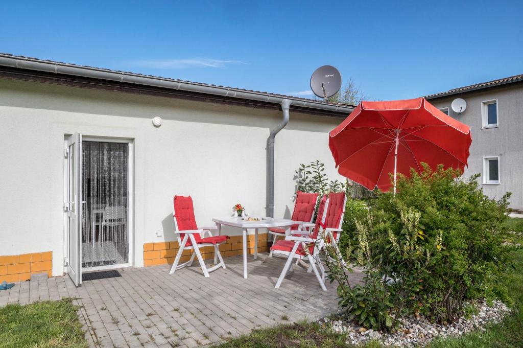 een patio met een tafel en stoelen en een parasol bij Strandnaher Bungalow in Dierhagen