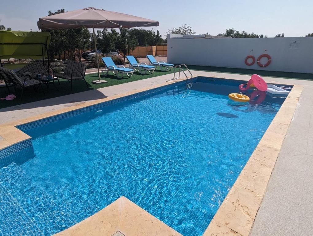 a child playing with a frisbee in a swimming pool at Falaj Hub Retreat in Umm Al Quwain