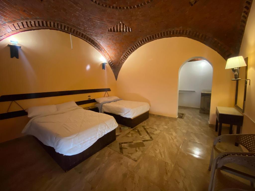 two beds in a room with an arched ceiling at Oasis inn House in Mandīshah