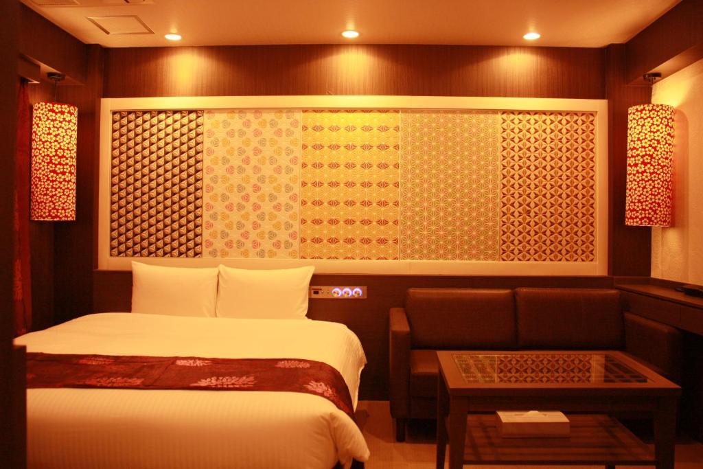 大阪市にあるhotel VR osakaのベッド2台とソファが備わるホテルルームです。