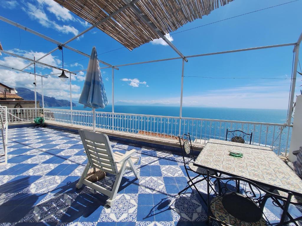 a patio with a table and an umbrella and the ocean at Casa dei sogni in Conca dei Marini