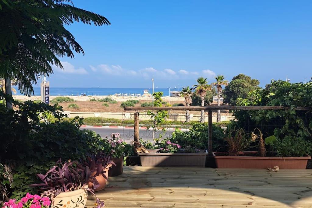 une terrasse avec des plantes et des fleurs et la plage dans l'établissement Beach House, à Ashdod