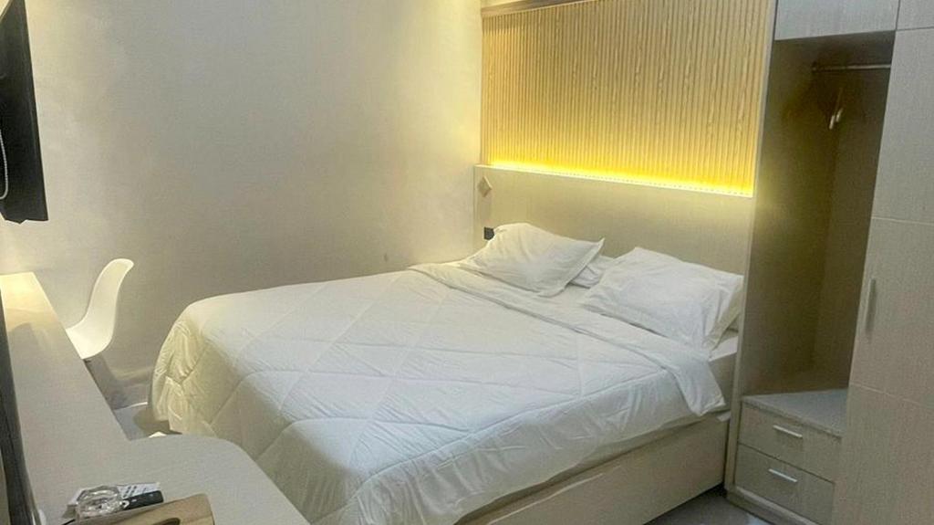 a bedroom with a white bed with a yellow window at UrbanView Hotel Wollangi Syariah Makassar in Makassar
