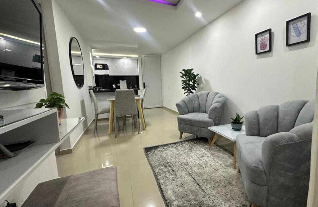 ein Wohnzimmer mit einem Sofa, Stühlen und einem Tisch in der Unterkunft CALI Acogedor y Nuevo apartamento cerca de Jardin plaza, con piscina, parqueadero y aire acondicionado in Cali