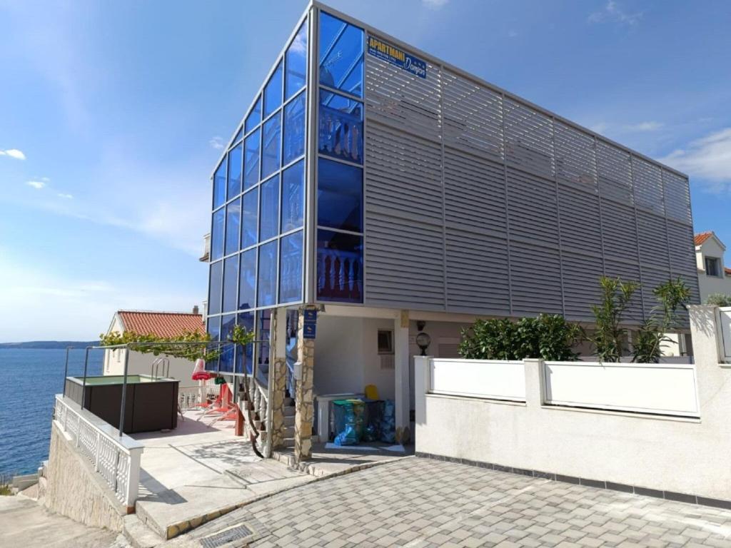 een gebouw met een glazen gevel naast het water bij Sea view Holiday Home in Okrug Gornji near Bocici Beach in Trogir