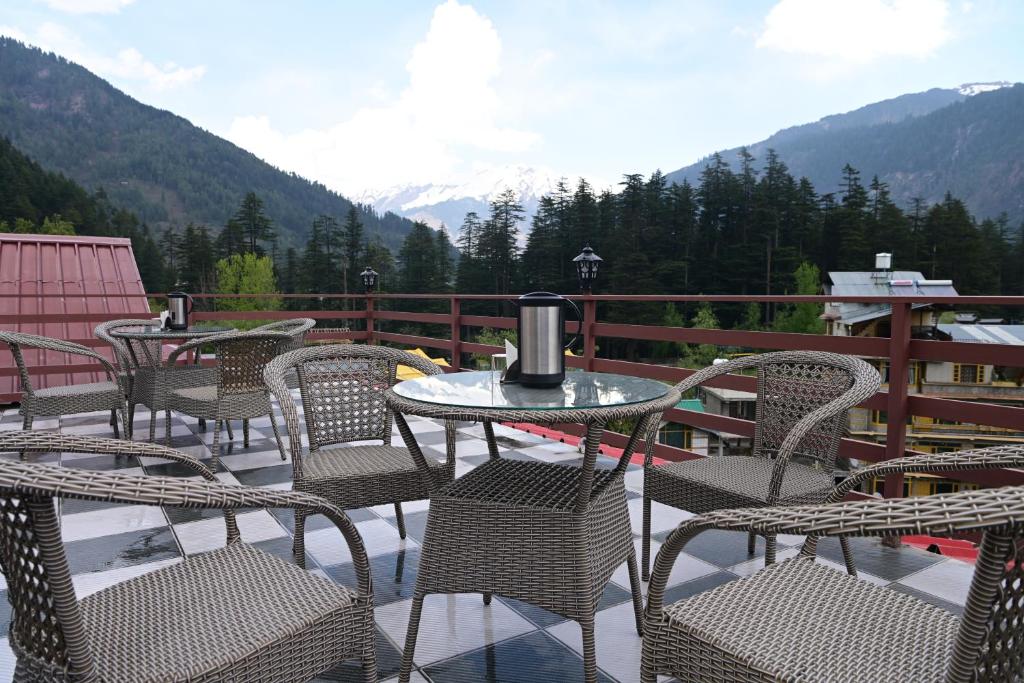 a table and chairs on a balcony with mountains at Hotel Nirvana Hills With Balcony Rooms And Open Terrace in Manāli