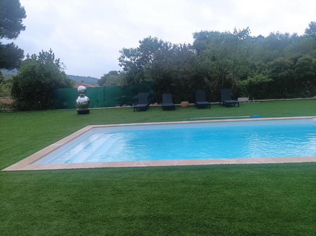 a swimming pool in a yard with chairs and grass at Villa de charme avec piscine in Toulon