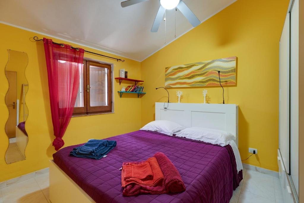 a bedroom with a purple bed and yellow walls at Home Holidays Pintadera 1 in Bosa