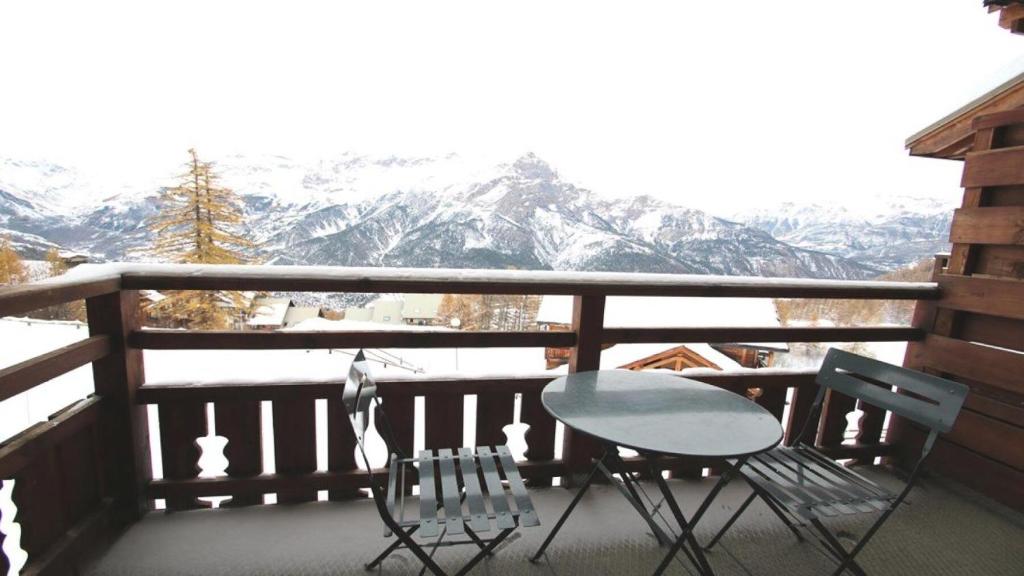 uma mesa e duas cadeiras numa varanda com montanhas cobertas de neve em Résidence Dame Blanche - 2 Pièces pour 6 Personnes 181 em Narreyroux