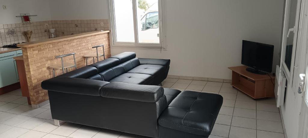 ein Wohnzimmer mit einem schwarzen Sofa und einem TV in der Unterkunft Le petit coin 2 in Carhaix-Plouguer