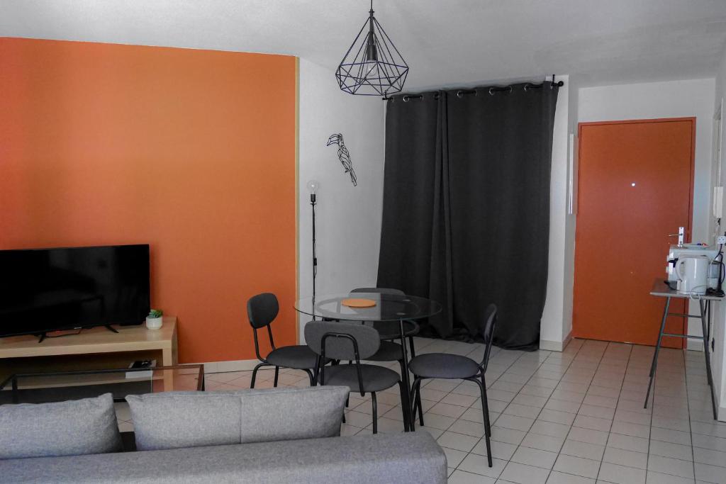 a living room with a couch and a table with chairs at Terracota - Cosi - Wifi - Parking - Terrasse in Saint-Orens-de-Gameville