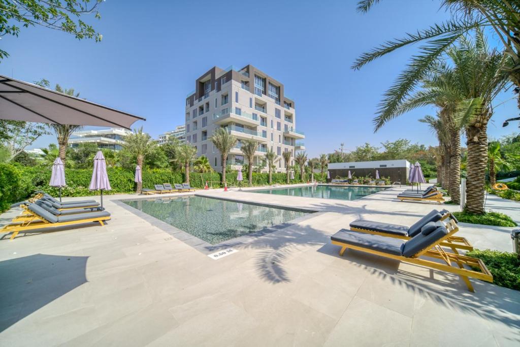 una piscina con tumbonas y un edificio en Stella Stays Al-Barari, en Dubái