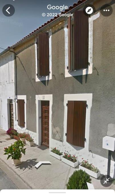 un bâtiment avec des portes marron et des fleurs devant dans l'établissement Agréable ancienne maison de ville, au Château-dʼOléron