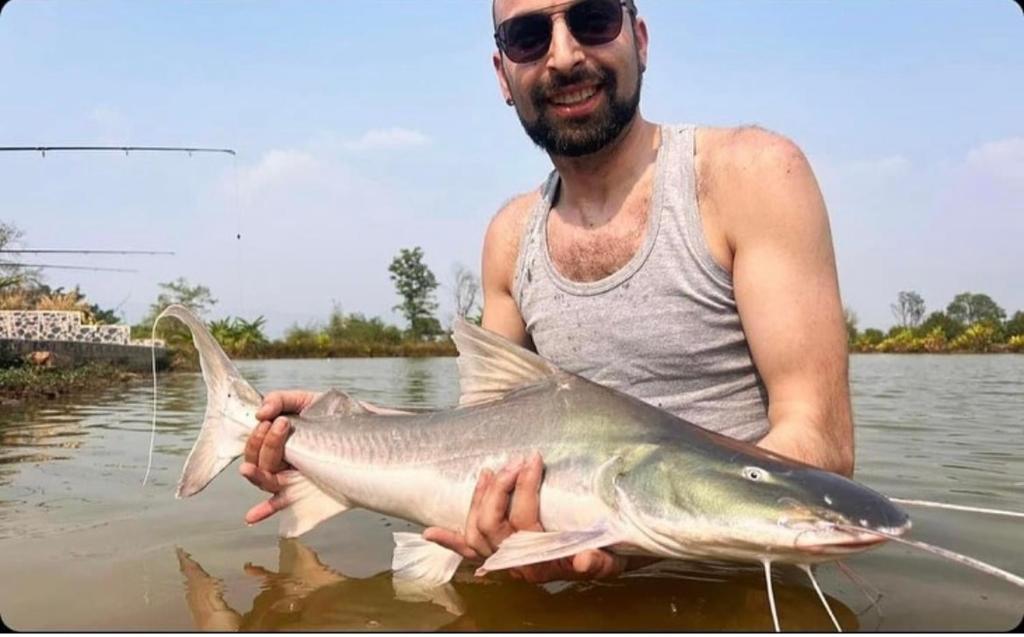 un hombre sosteniendo un pez grande en el agua en Chaiyaphum Monster Fishing Resort en Ban Huai Kum