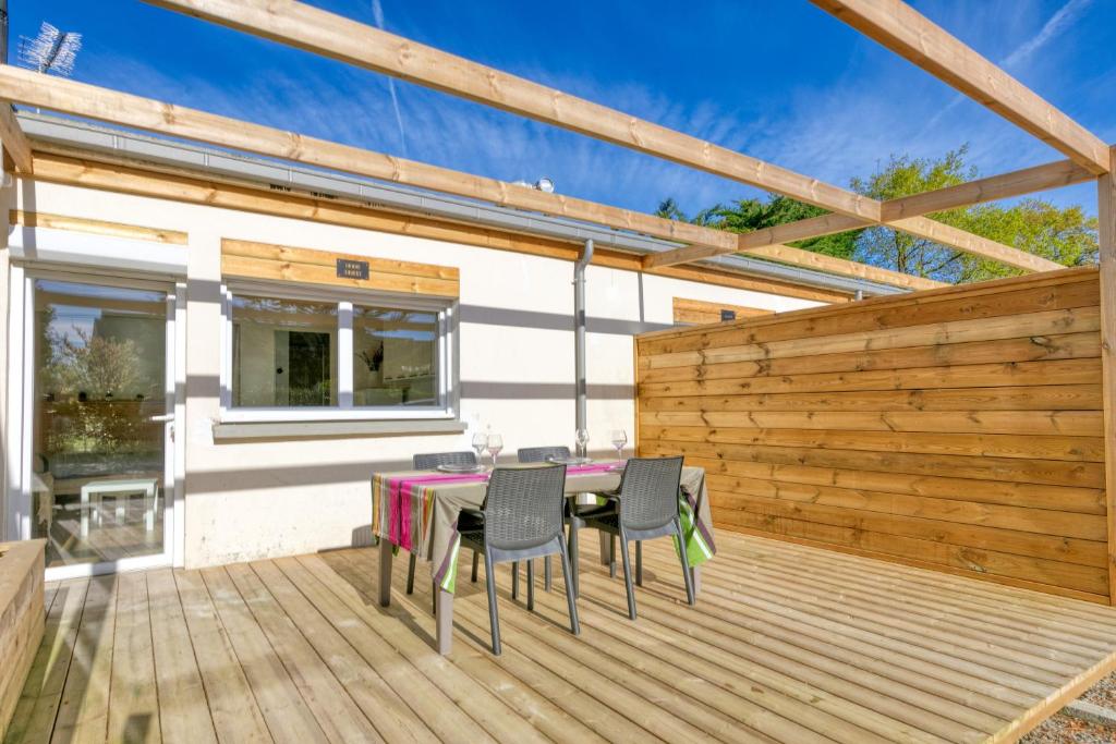 une terrasse en bois avec une table et des chaises dessus dans l'établissement La Dune de Sable Bonne Source, à Pornichet