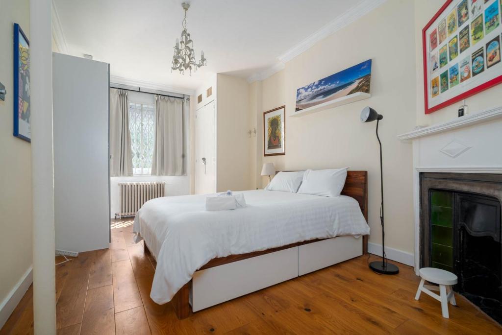 1 dormitorio con cama blanca y chimenea en GuestReady - Former Pub-Turned-One Bedroom Flat en Londres