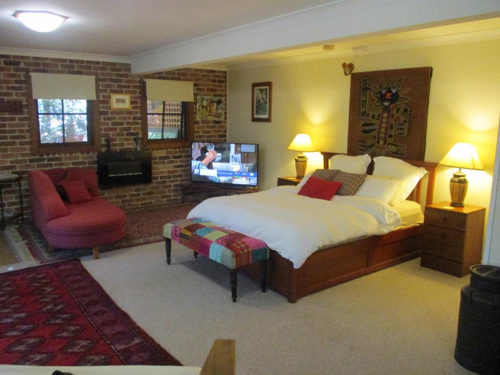a bedroom with a bed and a chair and a television at Warriwul Farmland Rural Retreat BnB, Curramore/Jamberoo in Jamberoo