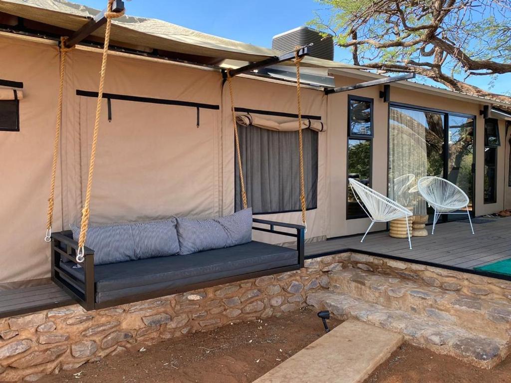 eine Veranda mit einem Schaukelbett und einer Terrasse in der Unterkunft Kameeldoring Glamping Namibia 