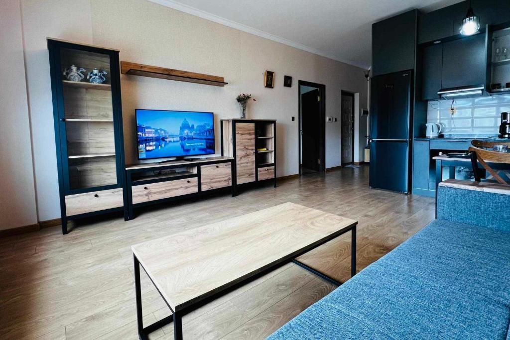 salon z telewizorem z płaskim ekranem i stołem w obiekcie Cosy modern city apartment in UB w Ułan Bator