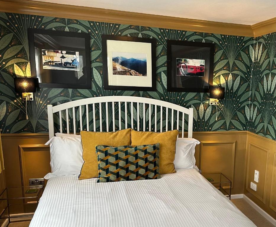 1 dormitorio con cama blanca y papel pintado con motivos florales en The Watermark, en Looe
