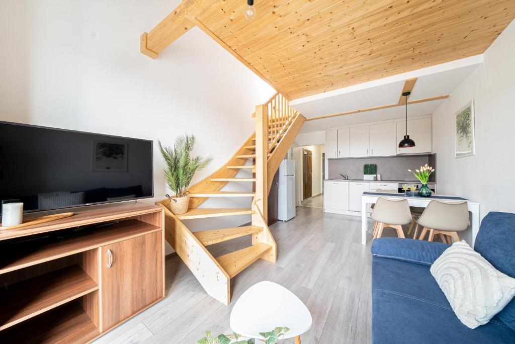 a living room with a blue couch and a staircase at Lipno Korzo Residence in Lipno nad Vltavou