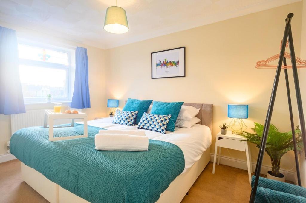 a bedroom with a large bed with blue pillows at Merriotts Court by Tŷ SA in Newport