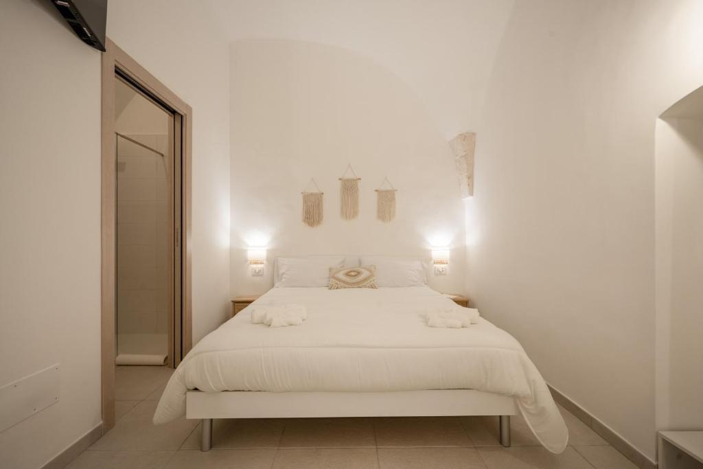 - une chambre blanche avec un lit blanc et un miroir dans l'établissement Dimora Giulia, luxury suite and spa, à Castellana Grotte