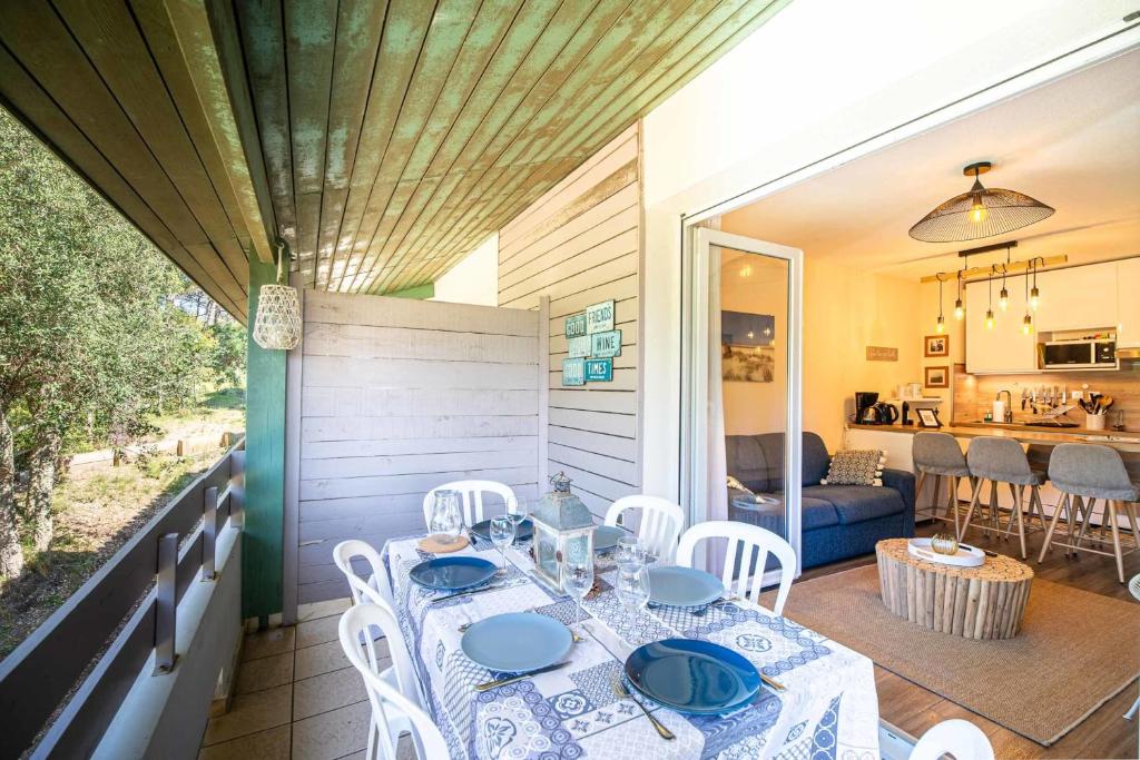 - une table à manger et des chaises sur une terrasse couverte avec une cuisine dans l'établissement Comfortable apartment with pool, à Moliets-et-Maa