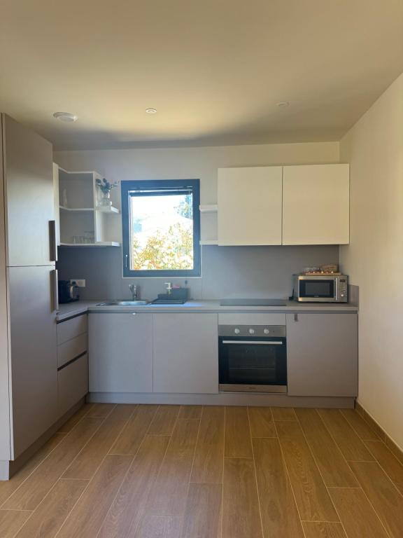 a kitchen with white cabinets and a window at Résidence CATALINA in Saint-Florent