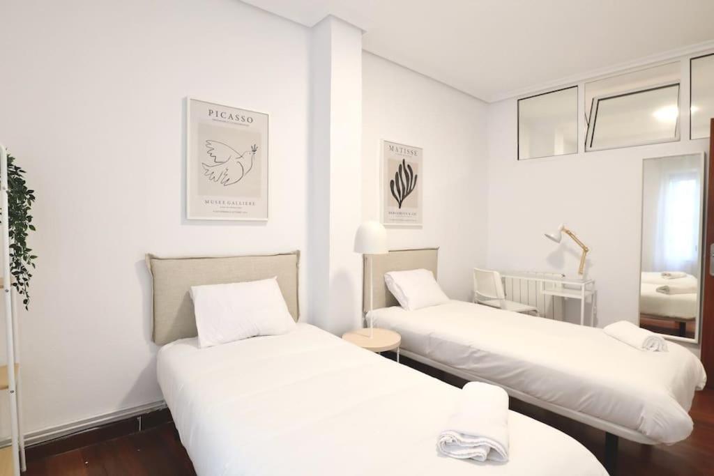 2 Betten in einem Zimmer mit weißen Wänden in der Unterkunft Notel Club - Corazón Urbano in Santander