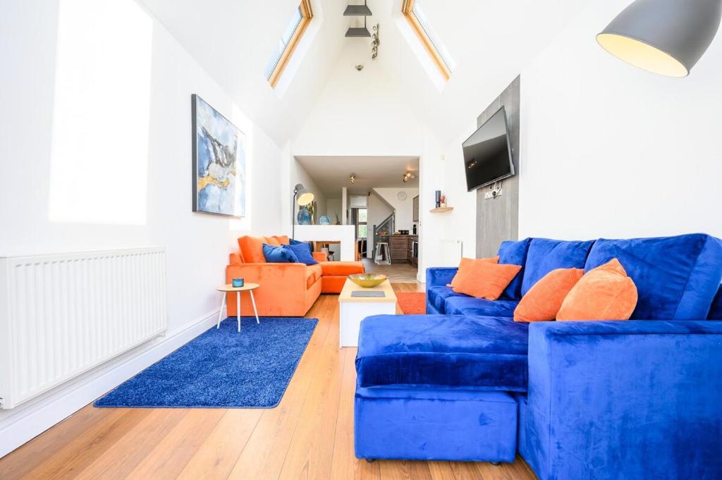 a living room with a blue couch and orange furniture at 2 bed with terrace - Llandaff Lofts by Tŷ SA in Cardiff