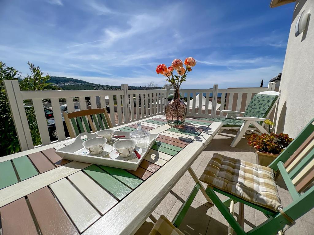 un tavolo con un vaso di fiori su un ponte di Léna - Maison, Terrasse vue mer, Clim - by TGB a Albitreccia