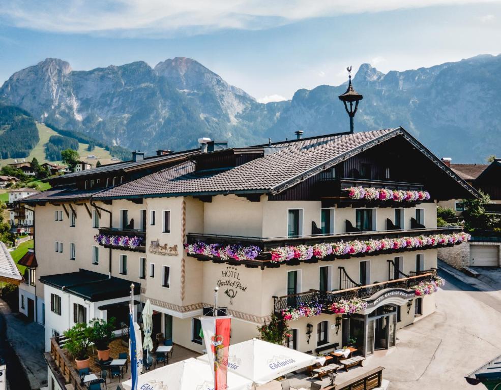 ein Hotel in den Bergen mit Blumen an den Fenstern in der Unterkunft Hotel Post Abtenau in Abtenau