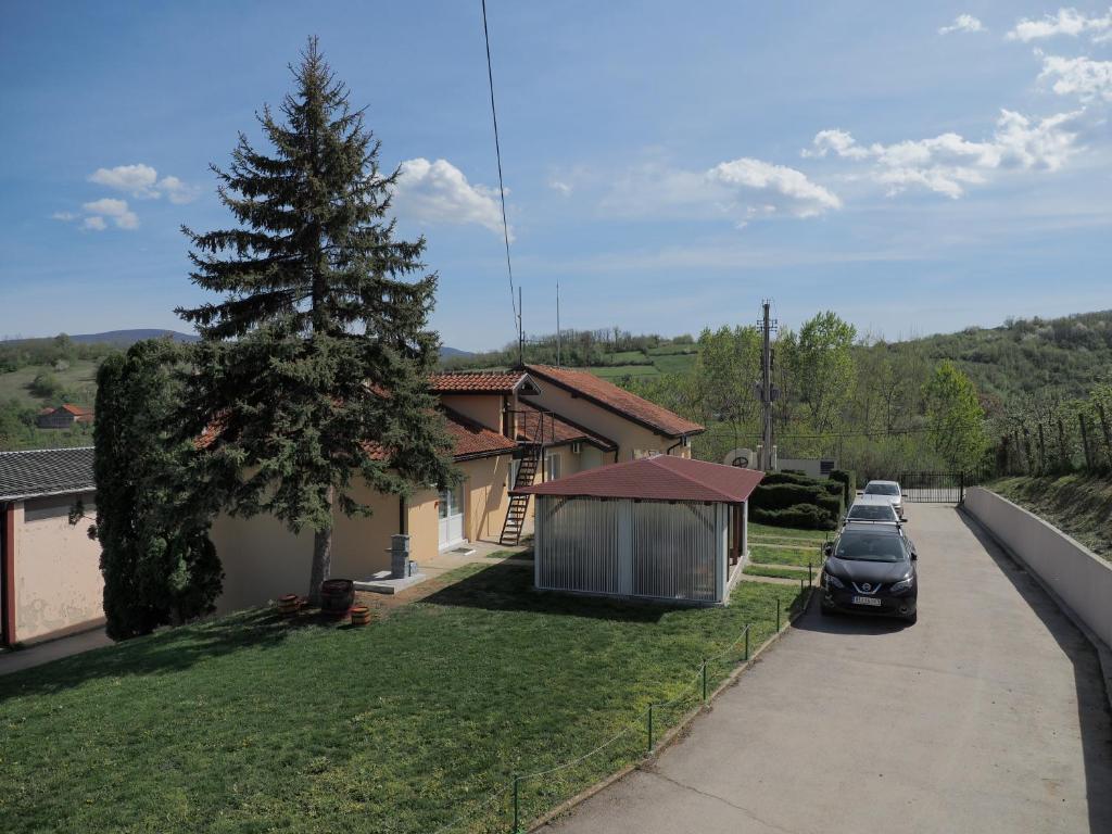 a house with cars parked in front of a driveway at Apartmani Rosica in Ribarska Banja