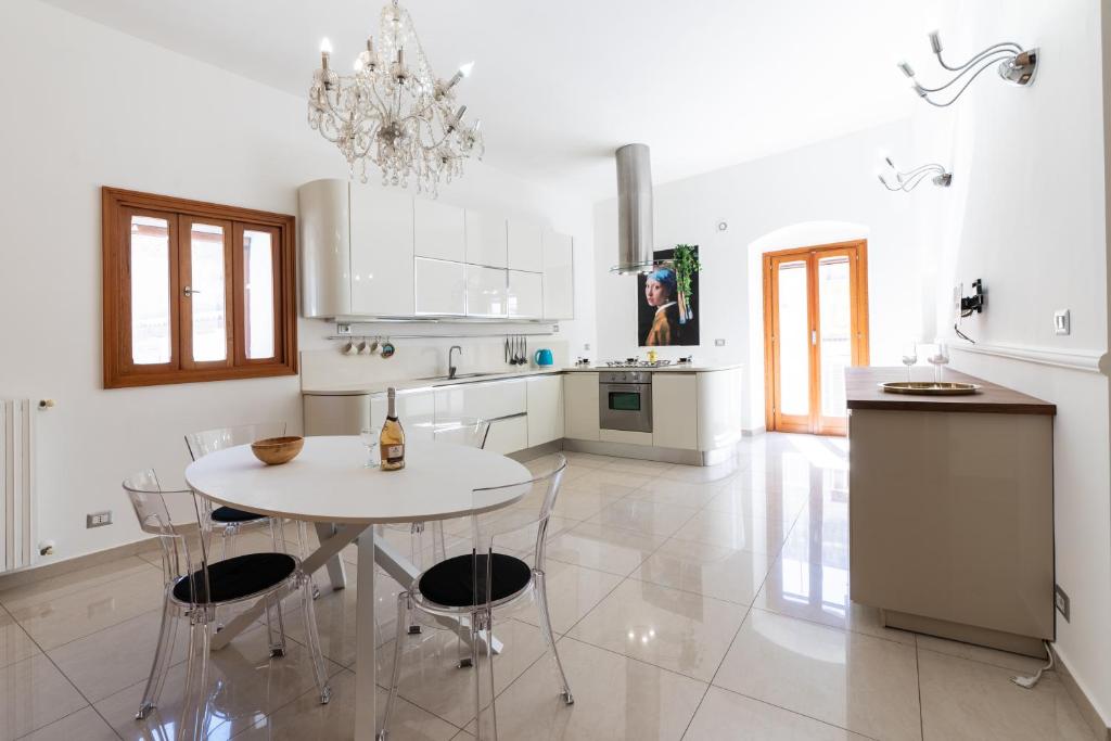 een witte keuken met een witte tafel en stoelen bij Il Viccio Apartment in Palo del Colle