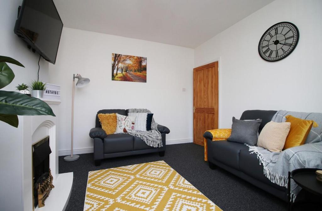 a living room with two couches and a clock on the wall at Bellevue by Tŷ SA - Modern 3 bed in Newport in Newport