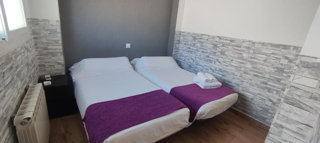 馬哈達翁達的住宿－埃斯科里亞爾旅館，一间小卧室,配有两张床和砖墙