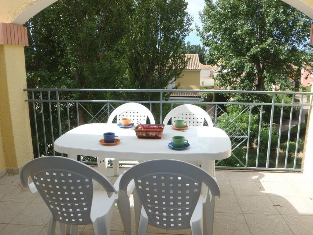 une table blanche et des chaises sur une terrasse dans l'établissement APPT 2 PCES MEZ 46m2 + TERRASSE 7m2 REF 4018, à Le Castellas