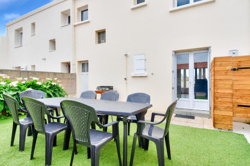 une table et des chaises sur une pelouse devant un bâtiment dans l'établissement 350 m de la plage - Appart avec grande terrasse, à Sion-sur-lʼOcéan