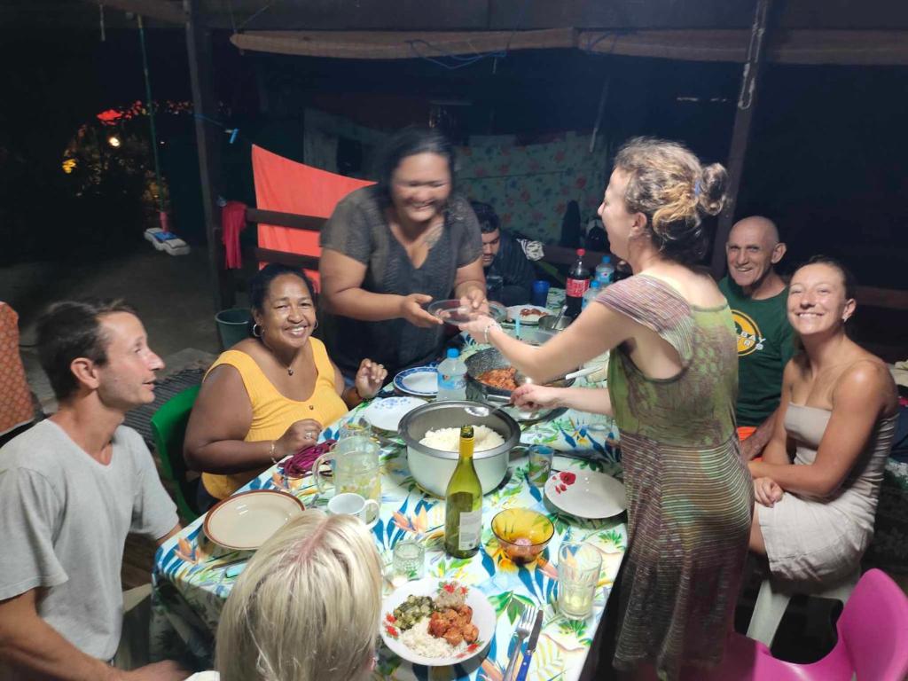 um grupo de pessoas sentadas à volta de uma mesa a comer em CHAMBRE CHEZ TAPUHERE LODGE em Fare