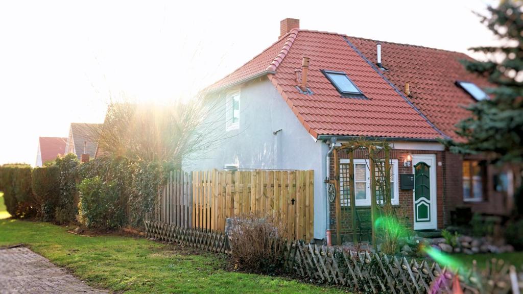 een wit huis met een rood dak en een hek bij Fehmarn Ostseeferien Feerjenkate Fehmarn 218 in Fehmarn