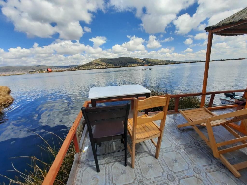 una mesa y sillas en un barco en el agua en Uros Titicaca UMA lodge, en Puno