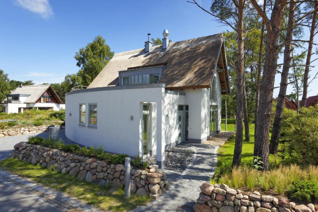 a white house with a stone wall at Lotsenstieg 04 in Ostseebad Karlshagen