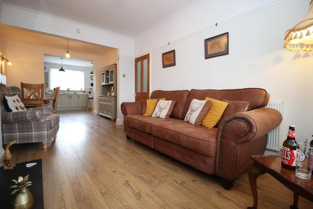 a living room with a brown couch and a table at Nessa’s Nook by Tŷ SA - Newport in Newport