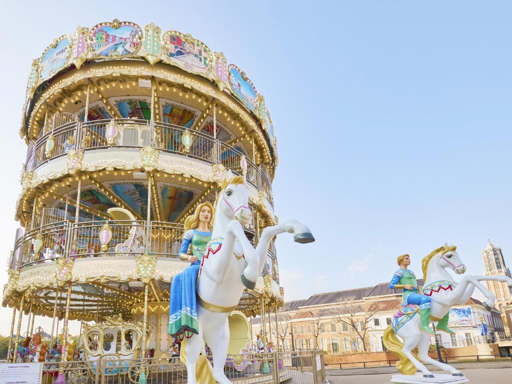 a carnival ride with two white horses in front of a building at Hotel Amsterdam Huis Ten Bosch in Sasebo