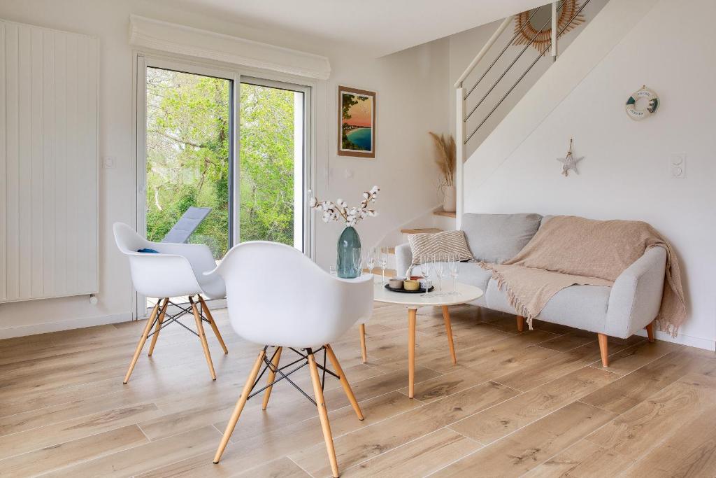 a white living room with a couch and a table at Maison pour 8 sur la Riviera Bretonne in La Forêt-Fouesnant