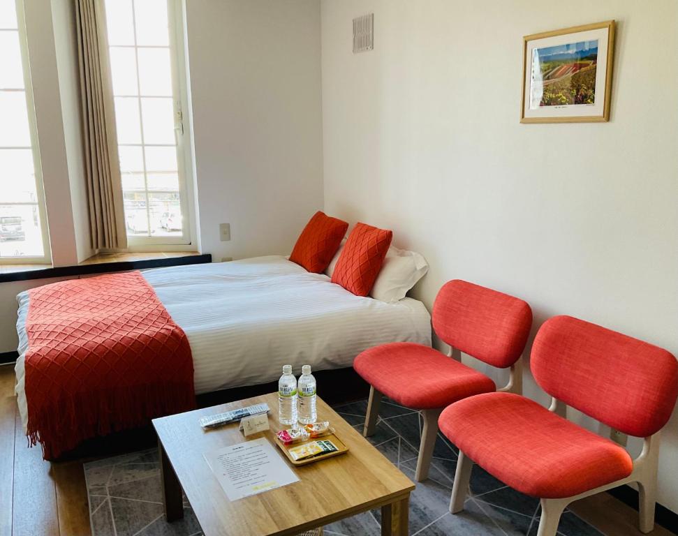 a hotel room with a bed and two red chairs at Warm House6 in Sapporo